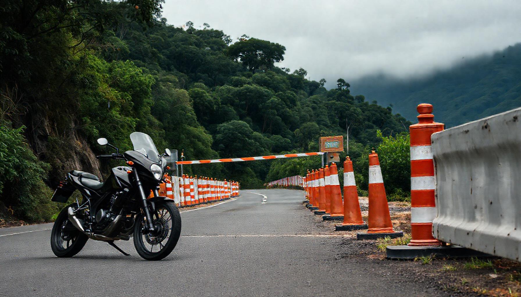 Moto preta parada diante de barreira com cones de sinalização bloqueando entrada de estrada de serra em Santa Catarina